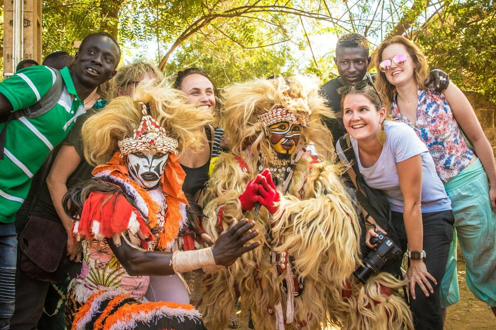Group of people posing with colorful costumed performers during a cultural festival in The Gambia.