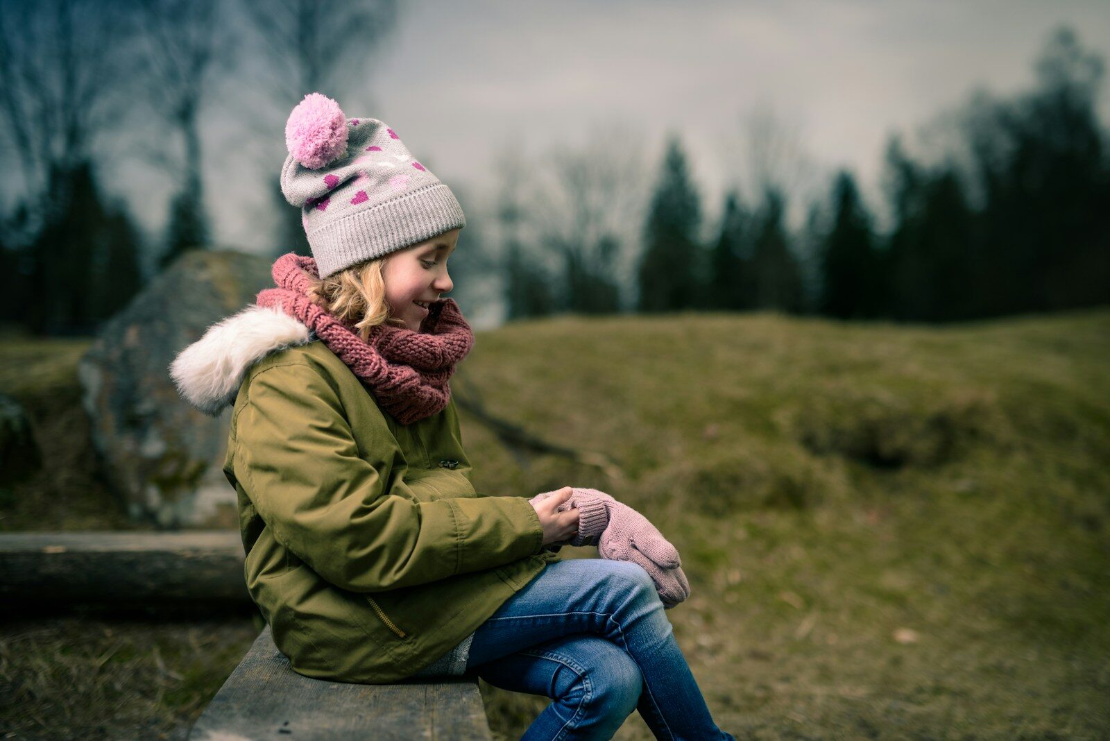 fillette souriante assise sur un banc marron